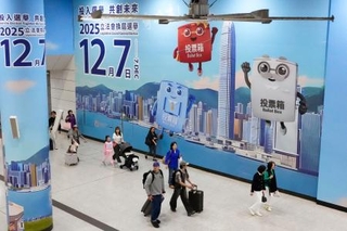 　駅構内の壁一面に張られた立法会選挙の投票を呼びかける広告＝６日、香港（共同）