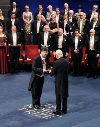 　ノーベル賞授賞式で、スウェーデンのカール１６世グスタフ国王（手前右）から生理学・医学賞のメダルと賞状を授与される坂口志文・大阪大特任教授（同左）＝１０日、ストックホルムのコンサートホール（代表撮影・共同）