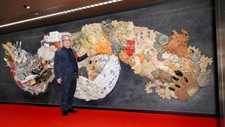 　原画や監修を手がけた陶板製の大型レリーフと写真に納まる漫画家大友克洋さん＝１５日午前、東京メトロ銀座駅構内