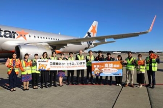 　駐機場で記念写真に納まるジェットスター・ジャパンの関係者ら＝１８日午前、成田空港