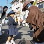 　天台宗の「全国一斉托鉢」で僧侶（右）に浄財を渡す親子＝１日午前、大津市