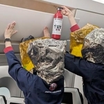 　日航の訓練施設で、荷物棚に消火器を向ける客室乗務員＝２日午後、東京都内