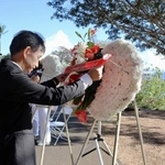 　８日、米ハワイ州フォード島で開かれた日米合同追悼式典で、献花する長徳英晶・駐ホノルル総領事（手前）と、コリンズ米ハワイ方面海軍司令官（共同）