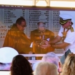 　中継会場で参加者が見守る中、真珠湾に献酒する静岡の医師菅野寛也さん（中央）ら＝８日、米ハワイの真珠湾（共同）