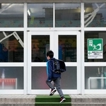 　学校が再開し、登校する青森県八戸市立江南小の児童。地震でガラス扉がひび割れた＝１０日午前７時４７分