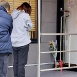 　現場となった店舗の出入り口に献花し、手を合わせる人＝昨年１２月、北九州市小倉南区