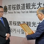 　若桜鉄道の矢部雅彦専務（右）から観光大使の任命状を受け取る尹熙一さん＝１１月、韓国・大田（共同）