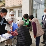 　市営住宅などへの入居に向けて、避難所で必要な物資を受け取る被災者（手前）＝１２日午前、大分市佐賀関