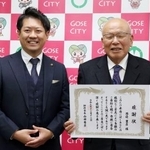 　奈良県御所市役所で山田秀士市長（左）から感謝状を受け取った西辺豊彦さん＝１２日午後