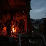 　イスラエル軍の攻撃で破壊された跡で、たき火で暖をとる人たち＝１２日、ガザ（ＡＰ＝共同）