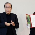 　スウェーデンから帰国し、ノーベル賞のメダルを手に取材に応じる京都大の北川進特別教授。右は授与された賞状＝１５日午前、大阪空港