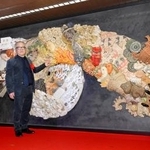 　原画や監修を手がけた陶板製の大型レリーフと写真に納まる漫画家大友克洋さん＝１５日午前、東京メトロ銀座駅構内