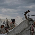 　避難者のテントの前で毛布にくるまるパレスチナの人＝１６日、パレスチナ自治区ガザ市（ＡＰ＝共同）