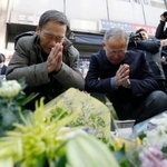 　大阪・北新地の放火殺人事件から４年となり、ビルの前で手を合わせる人たち＝１７日午前