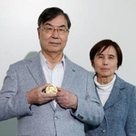 　スウェーデンから帰国し、ノーベル生理学・医学賞のメダルを手にする坂口志文大阪大特任教授。右は妻教子さん＝１７日午後、羽田空港