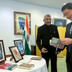 　故アシャさんの関連書籍を見る小野啓一駐インド大使。左はアシャさんの次男サンジェイさん＝１７日、ニューデリー（共同）