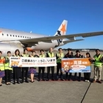 　駐機場で記念写真に納まるジェットスター・ジャパンの関係者ら＝１８日午前、成田空港