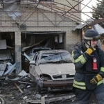 　ウクライナ南部ザポリージャで、ロシア軍の攻撃で損壊した住宅の前を歩く救急隊員＝１９日（ＡＰ＝共同）