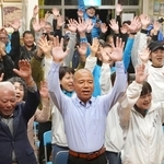 　沖縄県南城市長選で初当選を決め、万歳する大城憲幸氏（手前中央）＝２１日夜、南城市