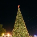 　広場に設置されたクリスマスツリーの前で写真を撮る女性たち＝２４日、パレスチナ自治区ベツレヘム（共同）