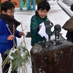 　「水木しげるロード」にある妖怪などのブロンズ像にしめ飾りを取り付ける子どもたち＝２６日、鳥取県境港市