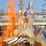 　成田山新勝寺の「納め札お焚き上げ」で、火柱にお札を投げ入れる山伏姿の僧侶＝２８日午前、千葉県成田市