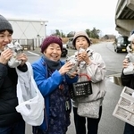 　石川県珠洲市の仮設住宅で振る舞われた焼き芋を笑顔で食べる女性＝２９日午前