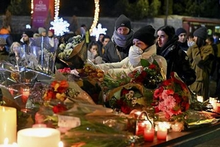 　１日、スイス南部バレー州クランモンタナの火災現場周辺で、花やキャンドルなどを手向ける人たち（ゲッティ＝共同）