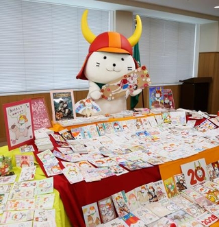 　届いた年賀状の山を前に羽子板を持って喜ぶ「ひこにゃん」＝７日午後、滋賀県彦根市役所