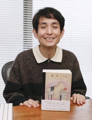 　出版した書籍と記念撮影する矢部太郎さん＝東京都内