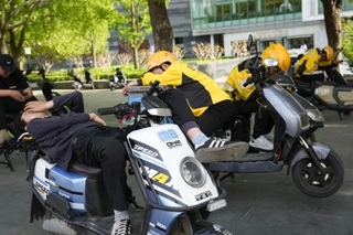 　バイクで仮眠する配達員ら＝２０２５年４月、北京（共同）