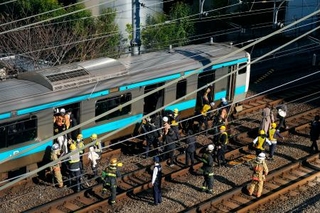 　高輪ゲートウェイ-田町間で停車したＪＲ京浜東北線の車両から線路に降りる乗客＝１６日午前９時７分、東京都港区