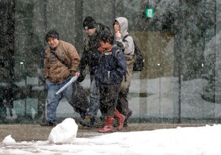 　雪が降る新潟県長岡市内を歩く人たち＝２０日午後