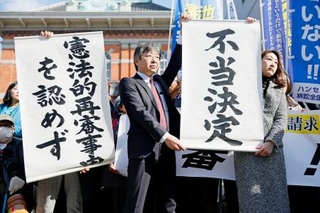 　「菊池事件」の再審開始を認めない熊本地裁の決定を受け、「不当決定」などと書かれた垂れ幕を掲げる弁護士＝２８日午後、熊本地裁前