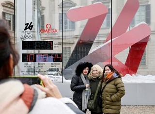 　ミラノ・コルティナ冬季五輪の開幕まで１週間となり、カウントダウン時計の前で記念撮影する人たち＝３０日、イタリア・ミラノ（共同）