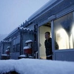 　能登半島地震の発生から２年、仮設住宅で降り積もる雪を見つめる男性＝１日午前７時２分、石川県珠洲市三崎町