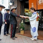 　明治時代の制服に身を包んだ配達員から年賀状を受け取るうどん店「三国一」の橋本有希野さん＝１日午前、東京都新宿区