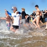 　和歌山県田辺市の扇ケ浜海水浴場で開催された新春初泳ぎで、勢いよく海へ入る参加者たち＝２日午前