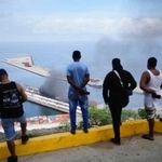 　ベネズエラの首都カラカス近郊の港で爆発の後、上る黒煙を眺める人たち＝３日（ＡＰ＝共同）