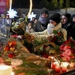 　１日、スイス南部バレー州クランモンタナの火災現場周辺で、花やキャンドルなどを手向ける人たち（ゲッティ＝共同）