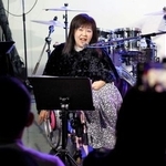 　車いすでステージに立ち、ハルウララへの感謝を歌に込める田中恵子さん＝２０２５年１２月、東京都千代田区