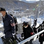 　エスカレーター事故の現場（右奥）前を通り、スキー場施設の家宅捜索に入る捜査員＝６日午前１０時４分、北海道小樽市