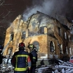 　ウクライナのキーウで、ロシアに攻撃された建物前に立つ消防隊員＝９日（ロイター＝共同）