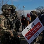 　９日、米ミネアポリスで、女性が死亡した現場付近を警備する移民・税関捜査局の職員ら（ロイター＝共同）