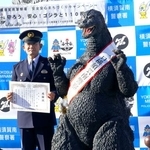 　神奈川県警横須賀南署の一日署長に委嘱された「ゴジラ」。左は小島博署長＝１０日午後、神奈川県横須賀市