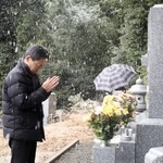 　スキーツアーバス転落事故で亡くなった次男・寛さんの墓に手を合わせる遺族会代表の田原義則さん＝１１日午後、京都府舞鶴市