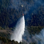 　延焼が続く山梨県上野原市の扇山で、消火活動を行う陸上自衛隊のヘリコプター＝１２日午前１０時５分（共同通信社ヘリから）