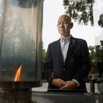 　「１・１７希望の灯り」を見つめる百々孝治さん。阪神大震災で妻子を亡くした＝２０２５年１１月、神戸市中央区の東遊園地