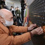 　「慰霊と復興のモニュメント」で、父喜禎さんの銘板を取り付ける昇和治さん＝１６日午後、神戸市中央区