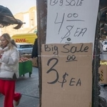 　米ニューヨークの商店街で価格表示の傍らを歩く通行人＝２０２５年１２月１２日（ゲッティ＝共同）